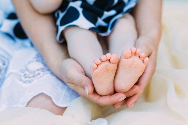 Mutter hält sanft Babybeine in der Hand