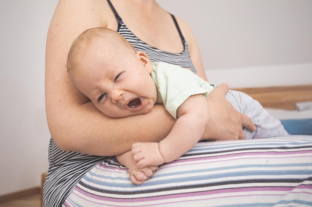 Mutter hält und schaukelt das Baby, das auf Fitball sitzt