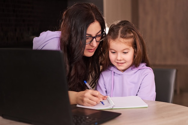 Mutter hilft ihrer Tochter bei den Hausaufgaben Fernunterricht Online-Unterricht zu Hause