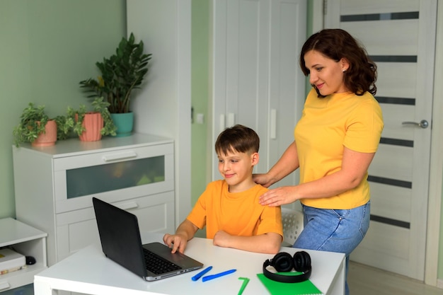 Mutter hilft Sohn, Hausaufgaben im Zimmer mit Laptop-Heimunterricht zu machen