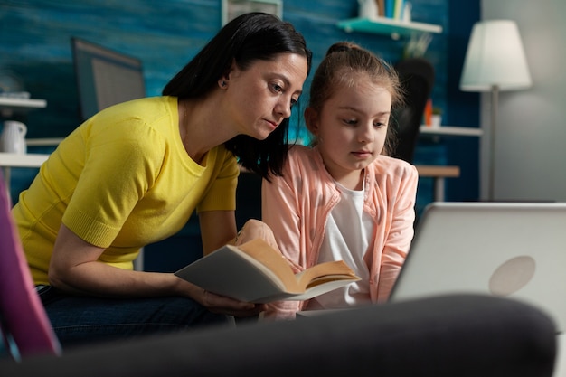 Mutter hilft Tochter bei den Schulhausaufgaben beim Lesen von Literaturbüchern