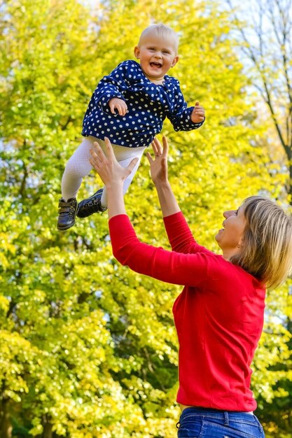 Mutter in einer warmen Jacke und gestrickten Mütze umarmt ihren kleinen Jungen geht im Herbstpark stilvoll blo