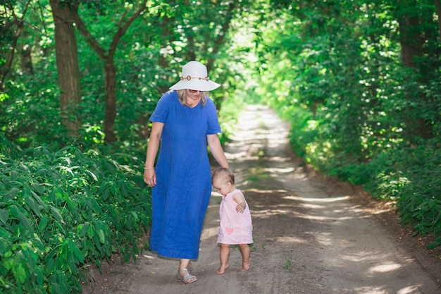 mutter in kleid und hut bringt einer kleinen tochter bei, im wald zu gehen