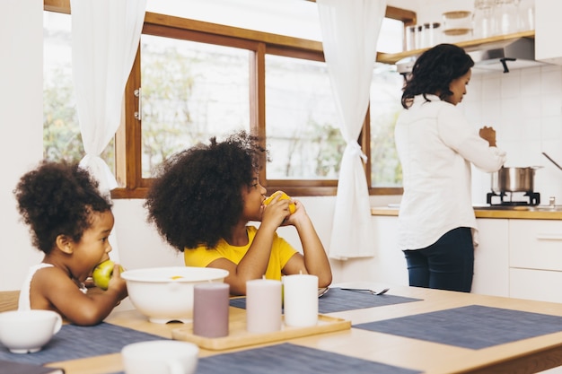 Mutter kocht für ihre beiden Kinder, die auf das Mittagessen warten. Konzept für alleinerziehende Mutter.