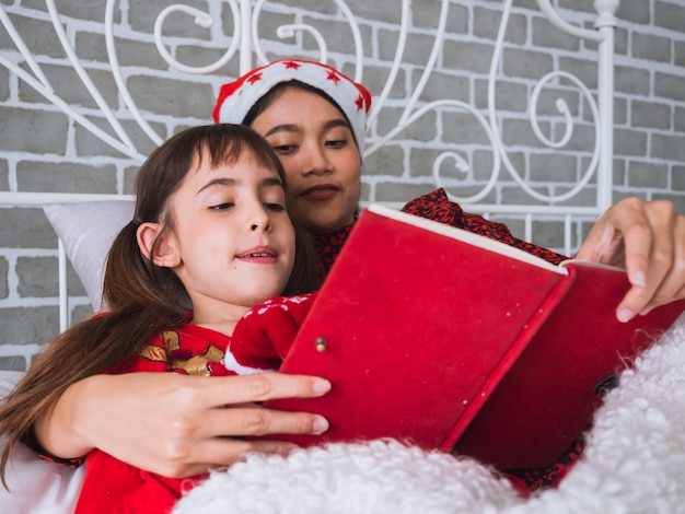 Mutter las ein Buch zu ihrer Tochter am Weihnachtstag, glückliches Familienkonzept