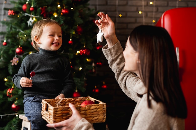Mutter lehrt Sohn, wie man Weihnachtsbaum schmückt
