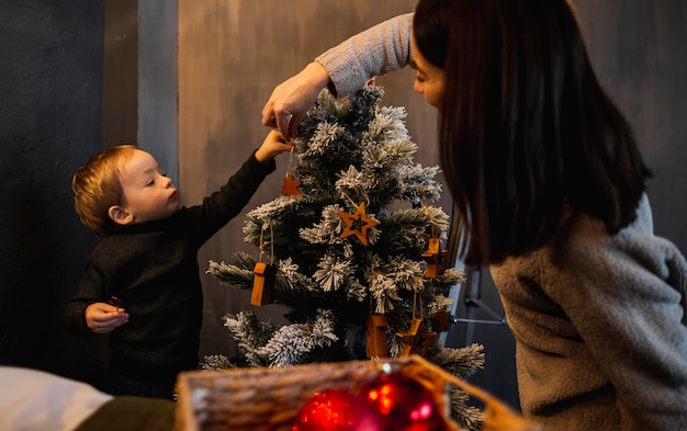 Mutter lehrt Sohn, wie man Weihnachtsbaum schmückt
