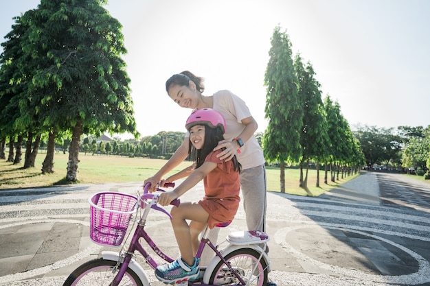 Mutter lehrt Tochter im Park Fahrrad zu fahren bike