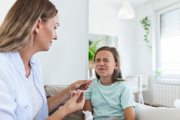 Mutter macht zu Hause bei ihrer kranken Tochter zu Hause einen Covid-19-Schnelltest. Mutter testet junges Mädchen auf Coronavirus-Infektion und führt einen COVID-19-Schnelltest durch