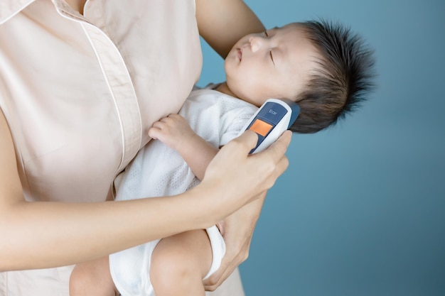 mutter misst die temperatur des babys mit einem elektronischen thermometer