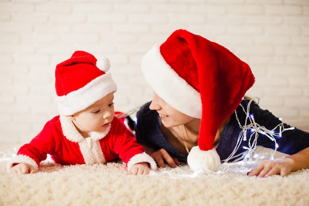 Mutter mit Baby im Weihnachtsmann-Kostüm in Girlanden verheddert