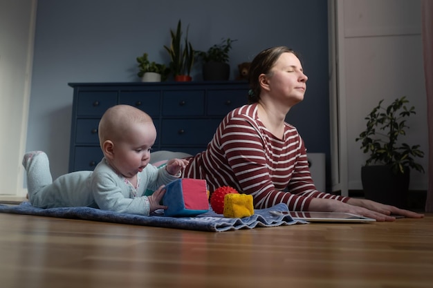 Mutter mit Baby macht Yoga zu Hause, um stark und gesund zu sein