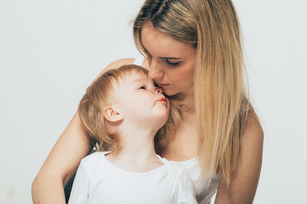 Mutter mit Babyporträtkind Frau mit blonden Haaren und Tochterkuss