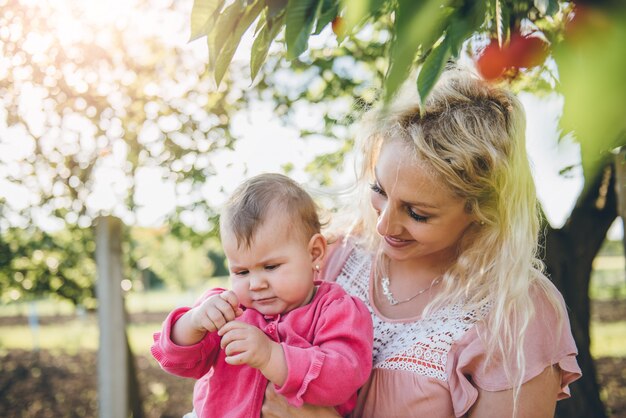 Mutter mit Babysammeln Cherry In Garden