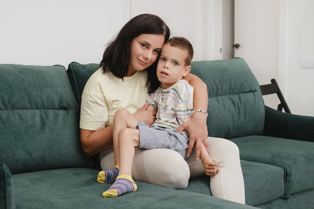 Mutter mit behindertem Kind auf dem Sofa Frau umarmt Junge mit zerebraler Lähmung zu Hause Mutter amüsiert sich