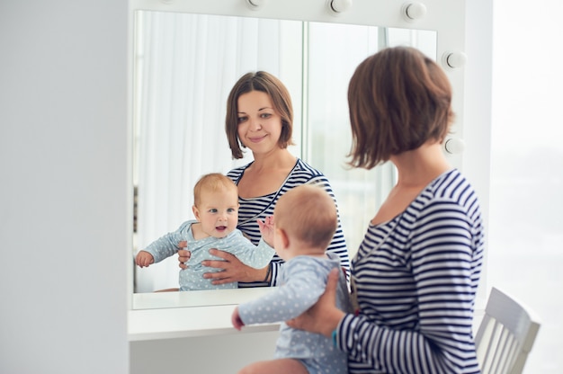 Mutter mit dem 8 Monate alten Baby schauen in einem Spiegel zu Hause