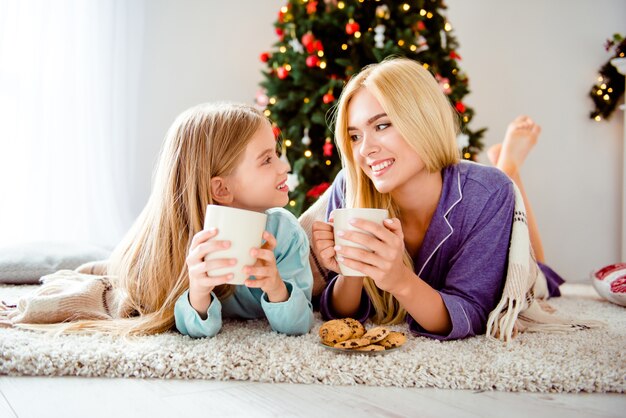 Mutter mit dem kleinen Mädchen, das Zeit zusammen nahe Weihnachtsbaum verbringt