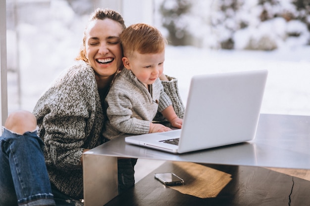 Mutter mit dem kleinen Sohn, der zu Hause an dem Computer arbeitet