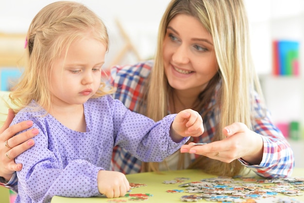 Mutter mit der Tochter, die Puzzlespiel sammelt