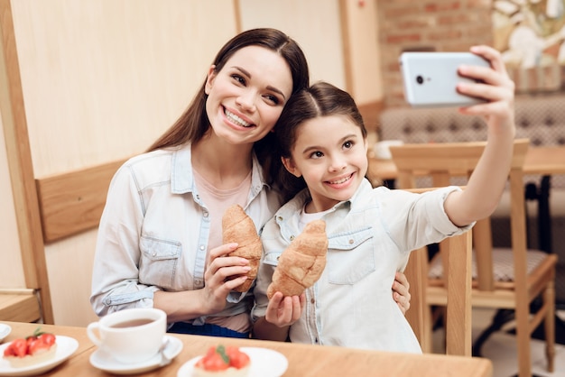 Mutter mit der Tochter, die Selfie in der Cafeteria nimmt.