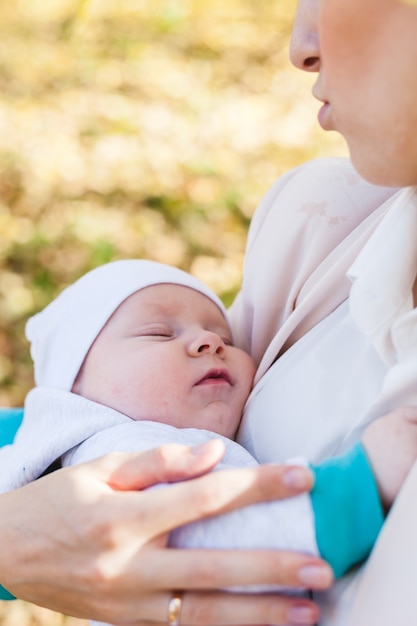 Mutter mit einem Baby, ein kleiner Junge geht im Herbst in den Park oder Wald. Gelbe Blätter, die Schönheit der Natur. Kommunikation zwischen einem Kind und einem Elternteil.