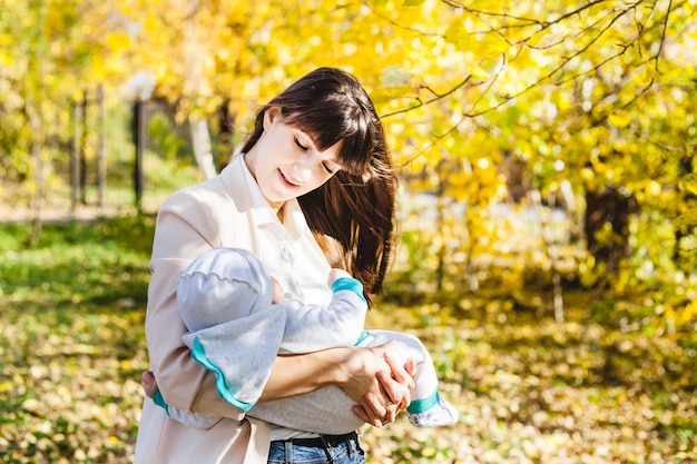 Mutter mit einem Baby, ein kleiner Junge geht im Herbst in den Park oder Wald. Gelbe Blätter, die Schönheit der Natur. Kommunikation zwischen einem Kind und einem Elternteil.