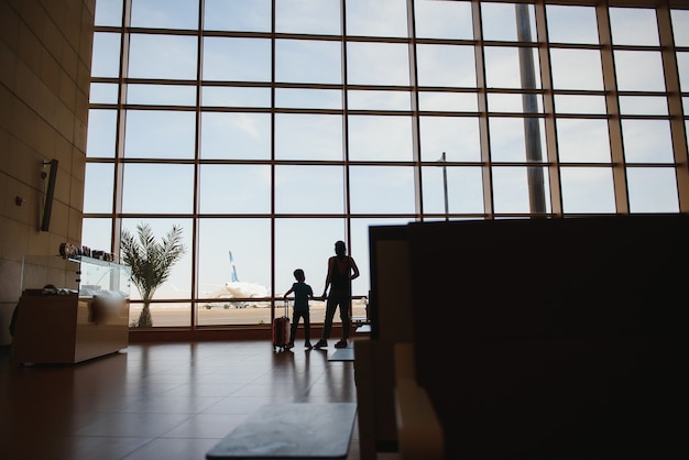 Mutter mit einem kleinen Sohn und einem Koffer am Flughafen.