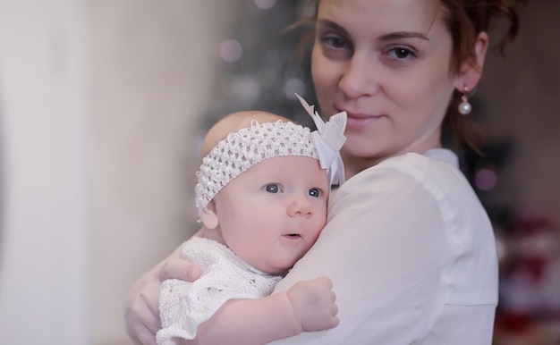 Mutter mit einem Neugeborenen in den Armen. Das Mädchen hält ein Baby vor dem Fenster. Neugeborenes in den Händen der Mutter.