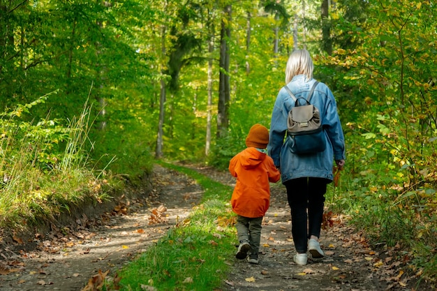 Mutter mit einem Sohn zu Fuß auf einer Straße in einem Wald