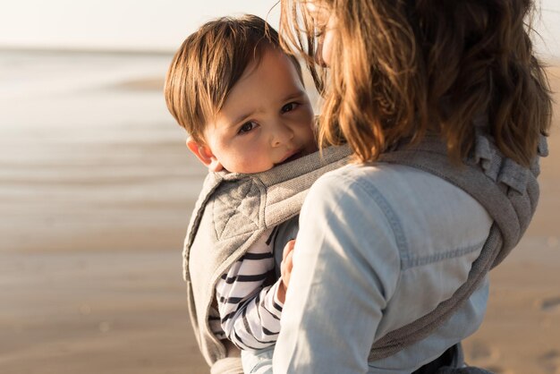 Mutter mit Ergobaby mit Kleinkind am Strand