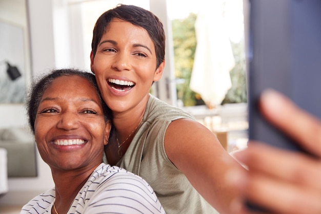 Mutter mit erwachsener Tochter, die zusammen Selfie zu Hause macht