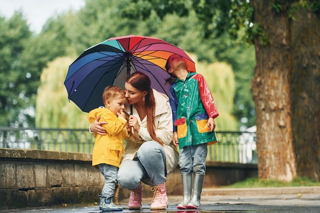 Mutter mit ihrem kleinen Sohn und ihrer Tochter spazieren nach dem Regen draußen im Park