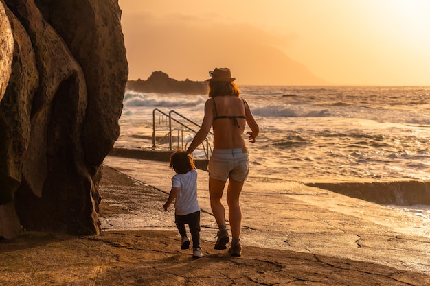 Mutter mit ihrem Sohn bei Sonnenuntergang im La Maceta-Felsenbecken auf der Insel El Hierro en la Frontera, Kanarische Inseln