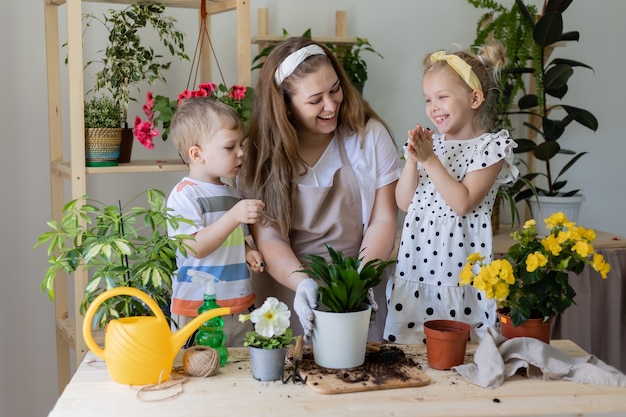 Mutter mit ihrem Sohn und ihrer Tochter in der Fastenpflanze oder verpflanzt Zimmerblumen