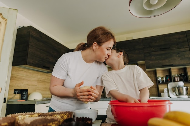 Mutter mit ihren kleinen Söhnen am Tisch in der Küche zu Hause bereitet gemeinsam den Teig zum Backen eines Feiertagskuchens vor