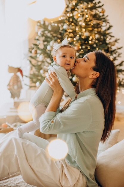 Mutter mit ihrer kleinen Tochter sitzt am Weihnachtsbaum