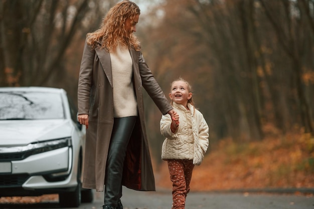 Foto mutter mit ihrer tochter ist draußen in der nähe eines elektroautos