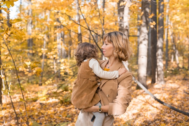 Mutter mit Kind in den Armen vor dem Hintergrund des Herbstnaturfamilien- und Jahreszeitkonzepts