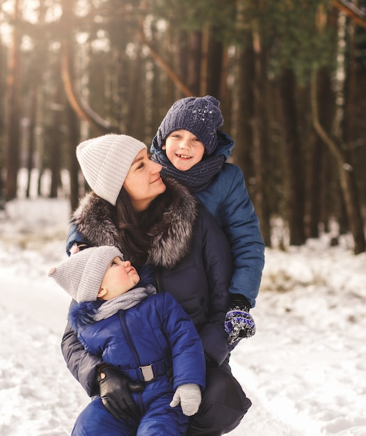 Mutter mit Kindern auf einem Spaziergang im Winterwald. Mutterschaft und Kindheit