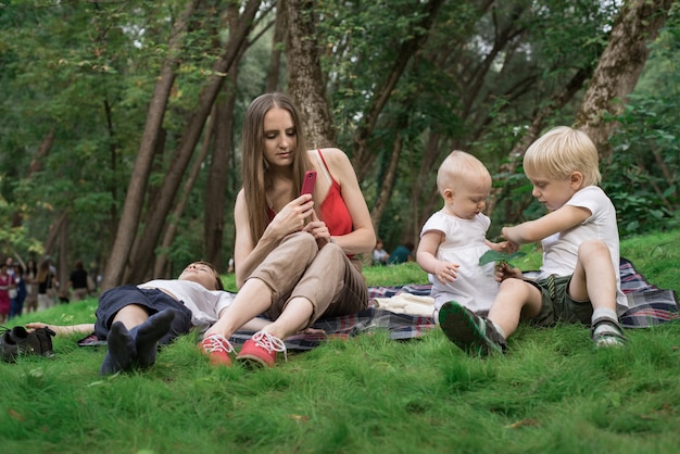 Mutter mit kindern beim picknick. mutter fotografiert kinder, wenn sie spielen