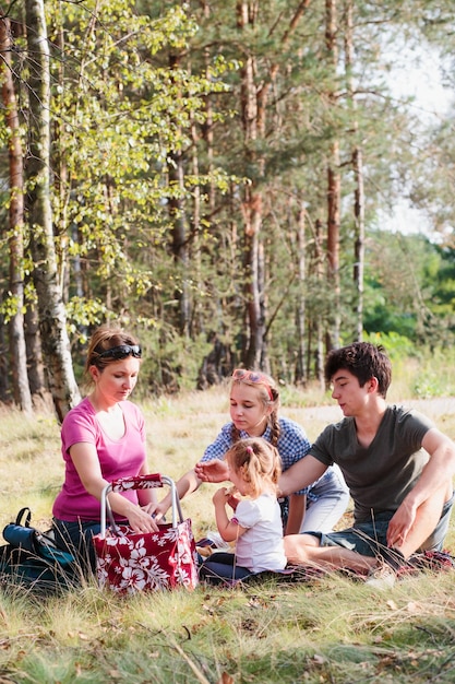 Mutter mit Kindern, die auf einem grasbewachsenen Feld Essen essen