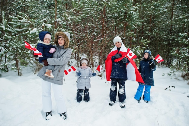 Mutter mit Kindern, die Flagge von Kanada auf Winterlandschaft halten