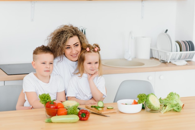 Mutter mit Kindern, die Gemüsesalat zu Hause vorbereiten