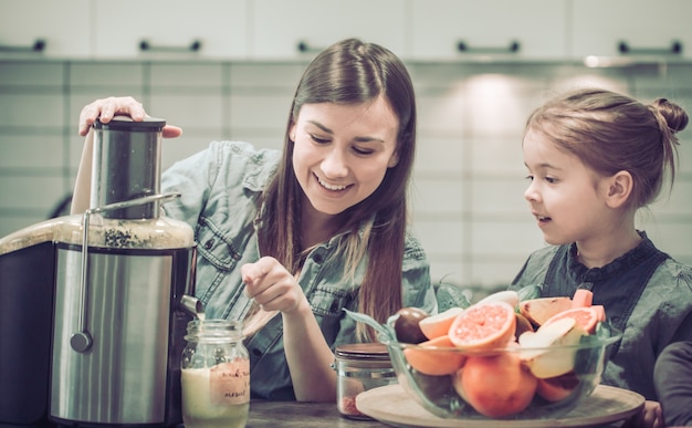 Mutter mit Kindern in der Küche bereitet Saft frisch zu