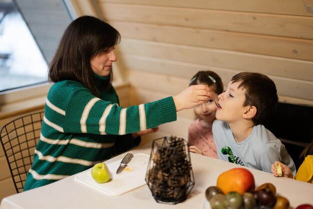 Mutter mit Kindern isst am Wochenende Früchte im Landhaus aus Holz