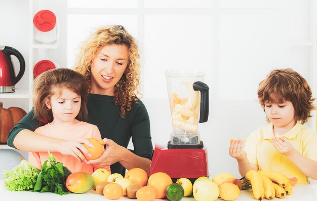 Mutter mit Kindern macht Smoothie in einer weißen Küche Familie Mutter und Kind Tochter und Sohn ble