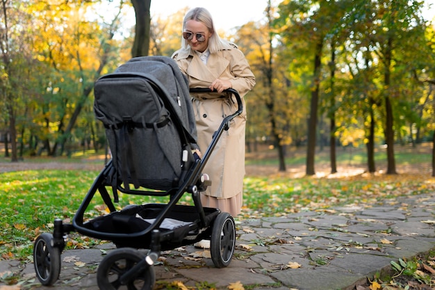 Mutter mit Kinderwagen, der im Herbstpark geht