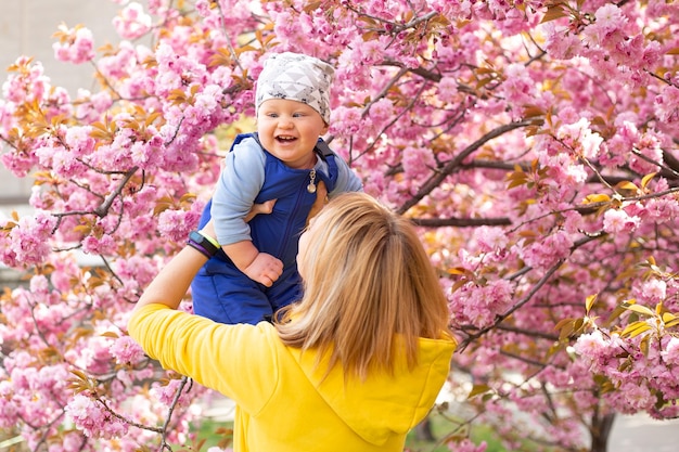 Mutter mit kleinem Sohn im Park, der nahe dem Sakura-Baum spielt