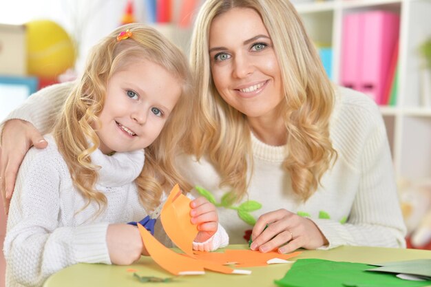 Mutter mit kleiner Tochter schneidet Figuren aus Papier