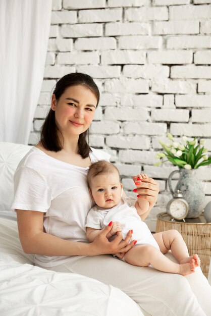 Foto mutter mit kleiner tochter sitzt auf dem bett